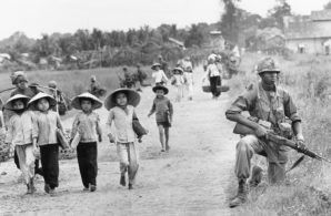1st Division soldier guarded Route 7 as Vietnamese women and children returned home to the village of Xuan Dien from Ben Cat, Vietnam, in December 1965.