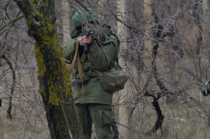 Russian soldier aims at unidentified armed gunmen moving close to Russian military base in Ukraine. 