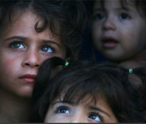 Syrian children look out the window of a refugee camp waiting for food rations. 