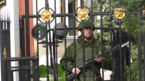 Russian soldier stands guard outside a Ukrainian military facility in Crimea - weapon with affixed bayonet at the ready. 