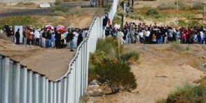 Illegal immigrants from Mexico swarm border fence with United States, near Texas. 