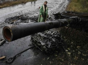 A Ukrainian soldier stands near a destroyed tank of pro-Russian separatists just outside the eastern Ukrainian town of Slaviansk July 7, 2014. 