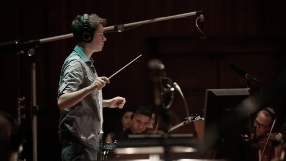 Composer Alex Redfern leading an orchestra at Warner Bros. Studios