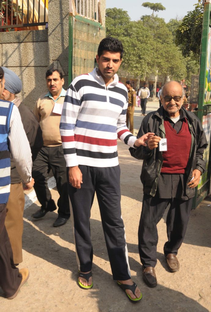 An old man being carried at a polling booth to cast his vote for the Delhi Assembly Election, in New Delhi on February 07, 2015.