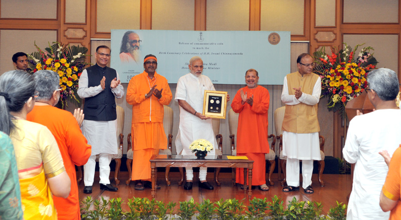 The Prime Minister, Mr. Narendra Modi releasing a commemorative coin to mark the birth centenary of Swami Chinmayananda, at a function, in New Delhi on May 08, 2015. The Union Minister for Finance, Corporate Affairs and Information & Broadcasting, Mr. Arun Jaitley, the Minister of State for Finance, Mr. Jayant Sinha, the Global Head of Chinmaya Mission, Swami Tejomayananda and the National Director of Chinmaya Yuva Kendra, Swami Mitrananda are also seen.